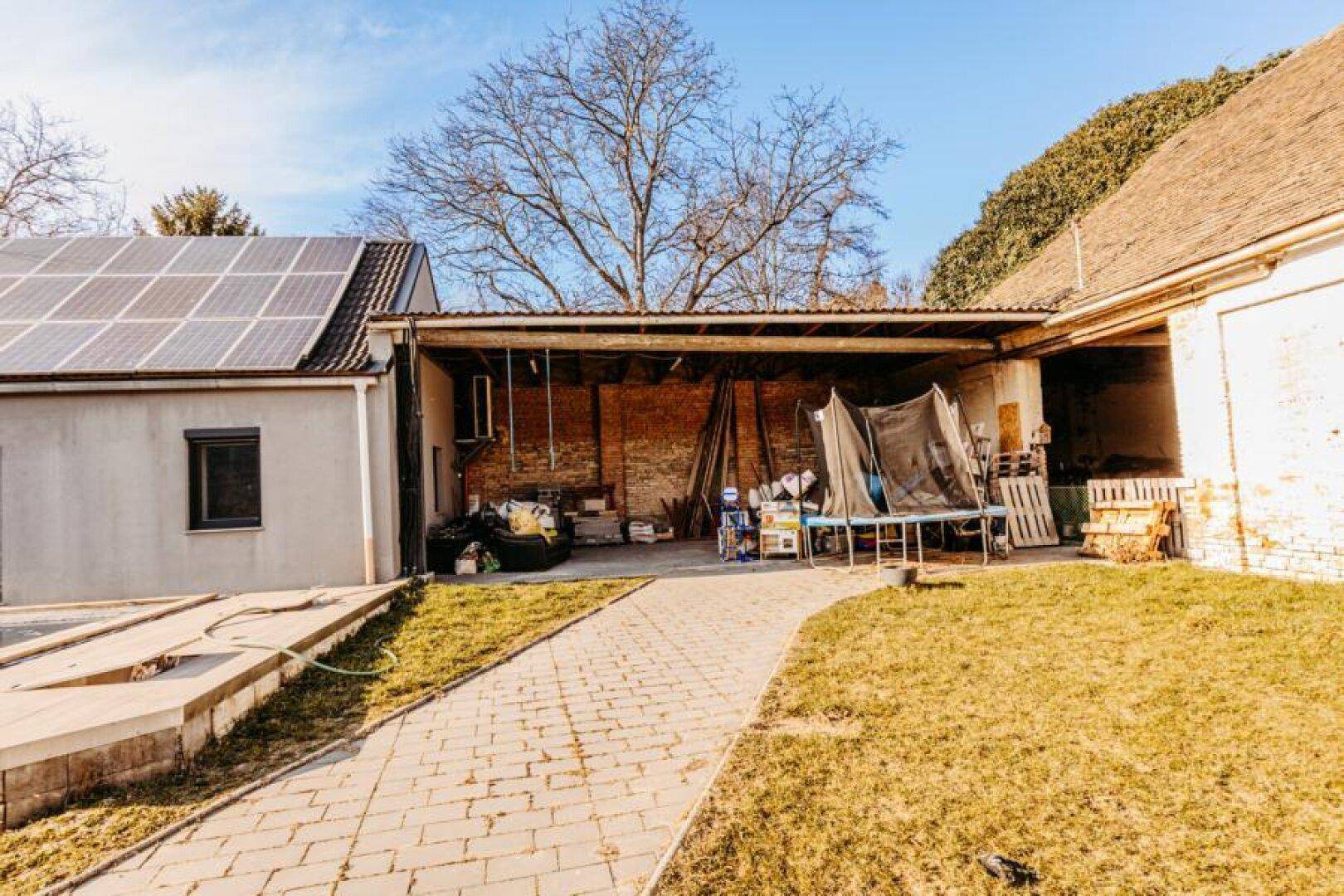 Rückansicht des Hauses mit Photovoltaikanlage auf dem Dach und einem offenen Unterstand.