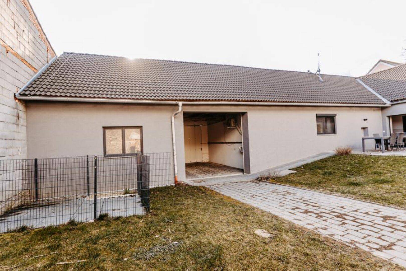 Offene Garage oder Lagerraum an der Seite des Hauses mit gepflastertem Zugangsweg.