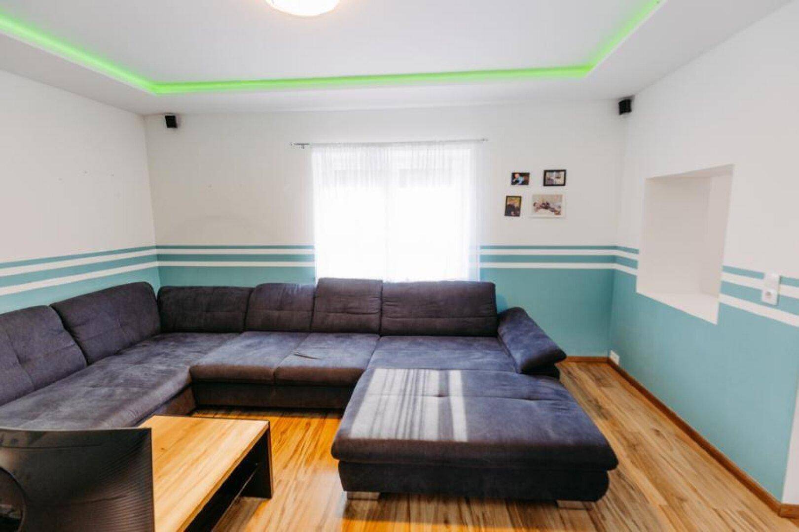 Gemütliches Wohnzimmer mit großem Ecksofa, Holzboden und indirekter Deckenbeleuchtung.