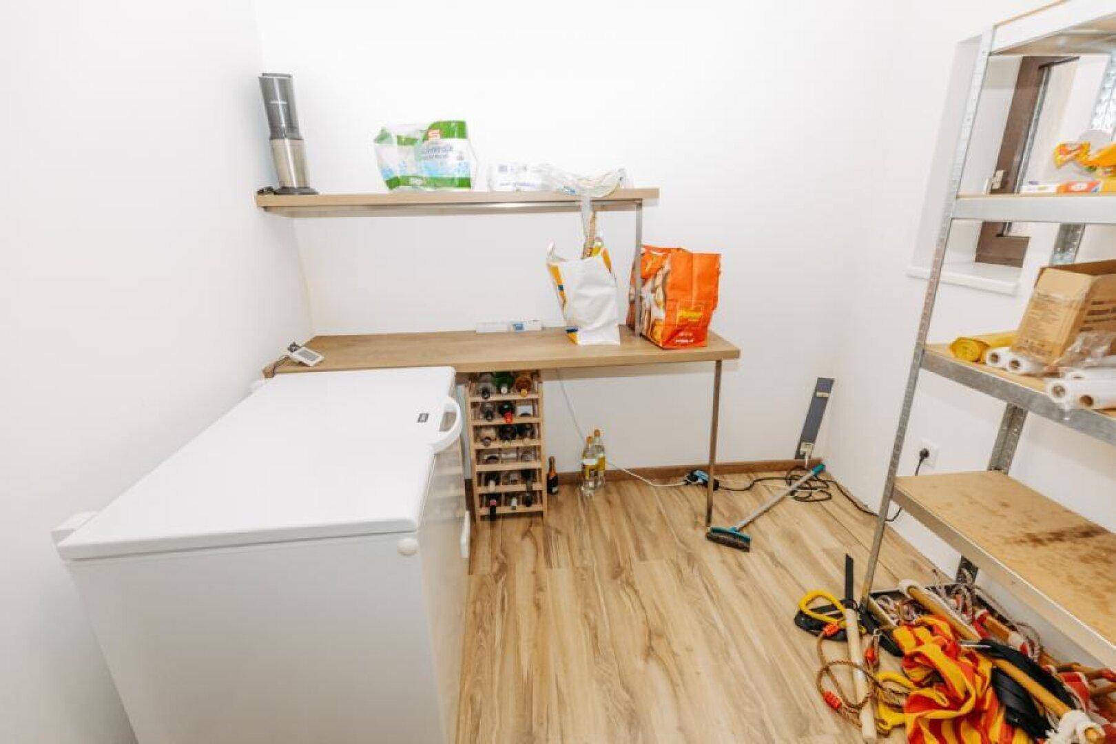 Geräumige Speisekammer mit Gefriertruhe, Arbeitsfläche und zusätzlichen Regalen.