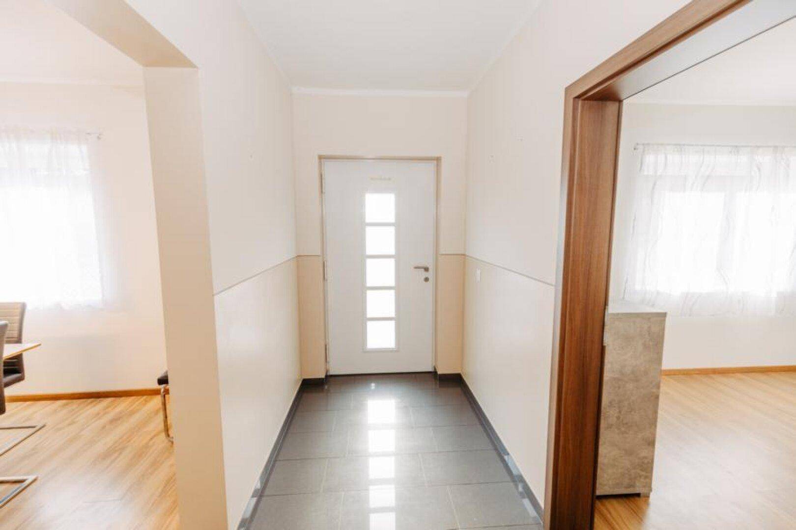 Heller Eingangsbereich mit Fliesenboden, weißer Haustür und Zugang zu weiteren Räumen.