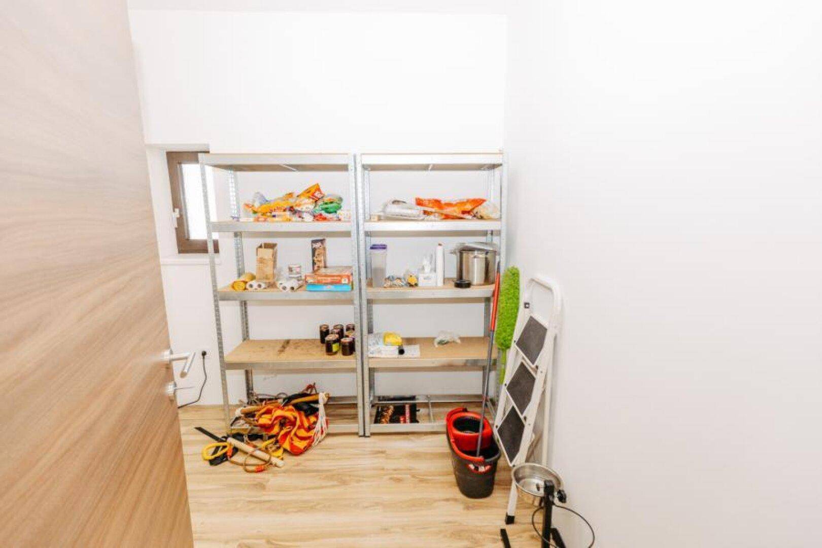 Gut organisierte Speisekammer mit Metallregalen, Vorräten und Reinigungsutensilien.