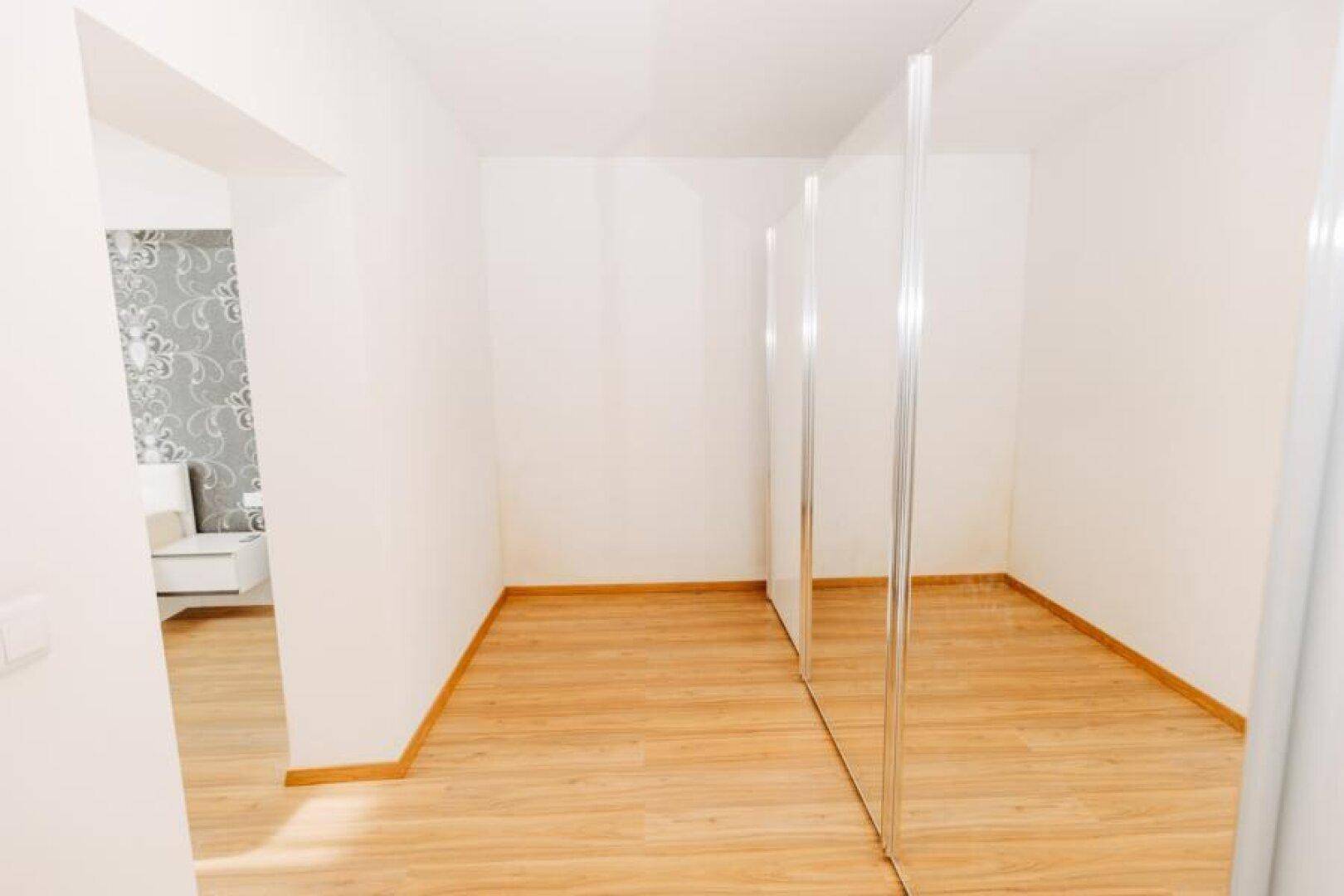 Geräumiges Zimmer mit Spiegelfronten und Holzboden, bereit für individuelle Einrichtung.