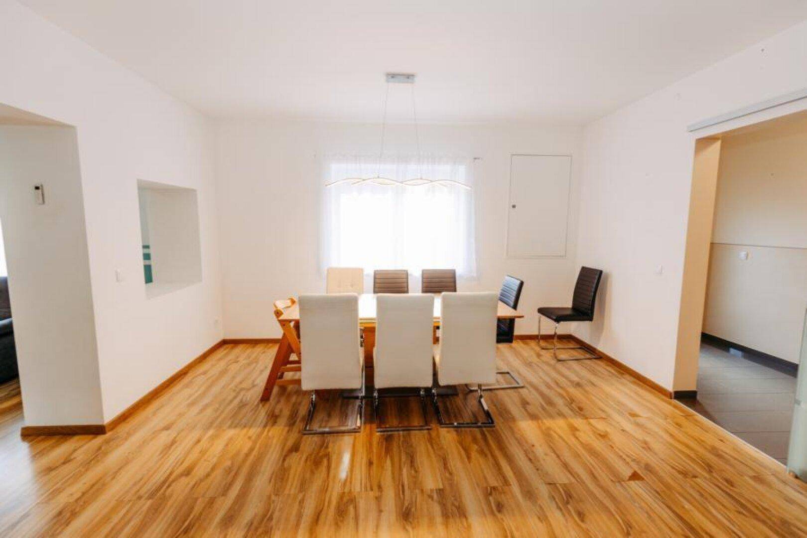 Geräumiger Essbereich mit Holzboden, großem Esstisch und viel Tageslicht durch das Fenster.