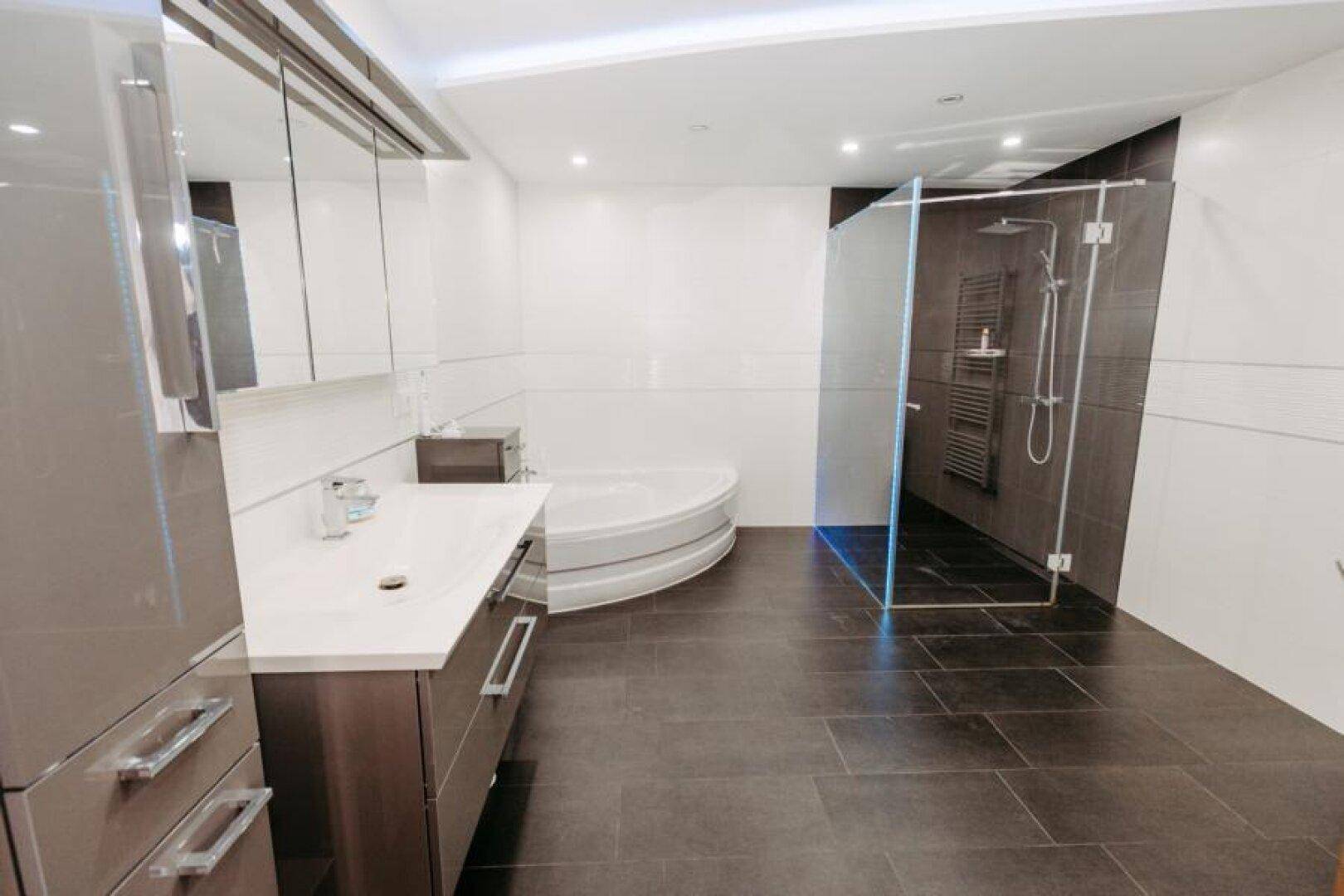 Modernes Badezimmer mit großer Eckbadewanne, begehbarer Dusche und Doppelwaschbecken.