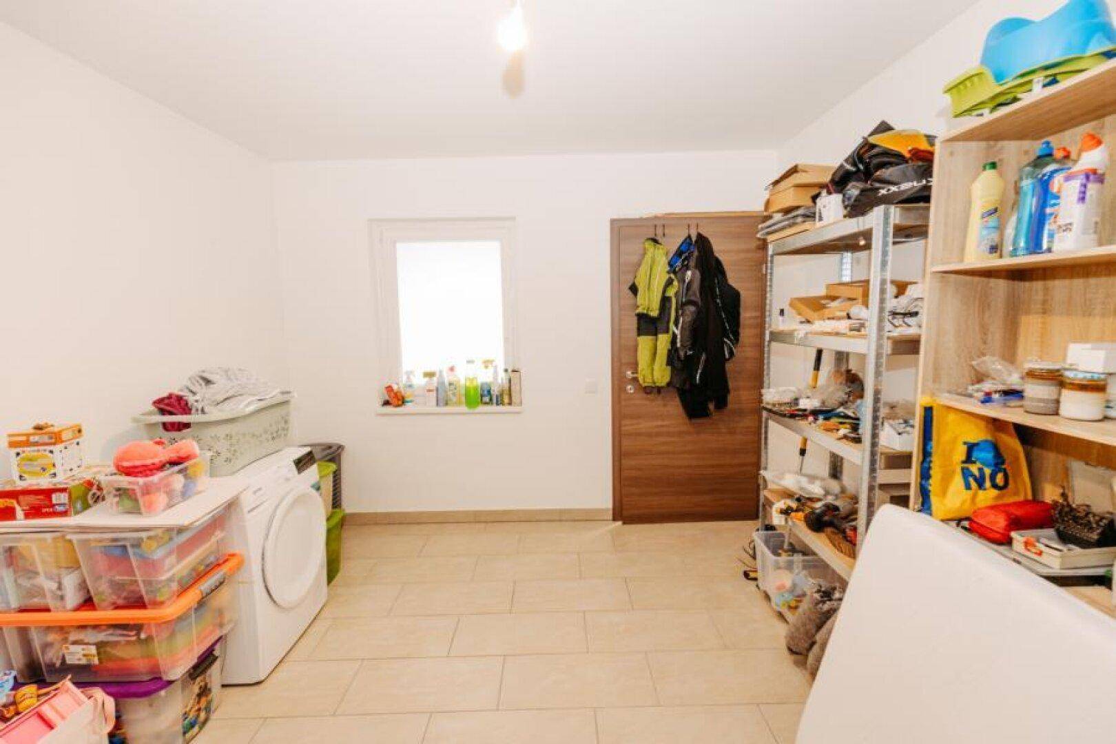 Praktischer Hauswirtschaftsraum mit Waschmaschine, Fenster und viel Stauraum.