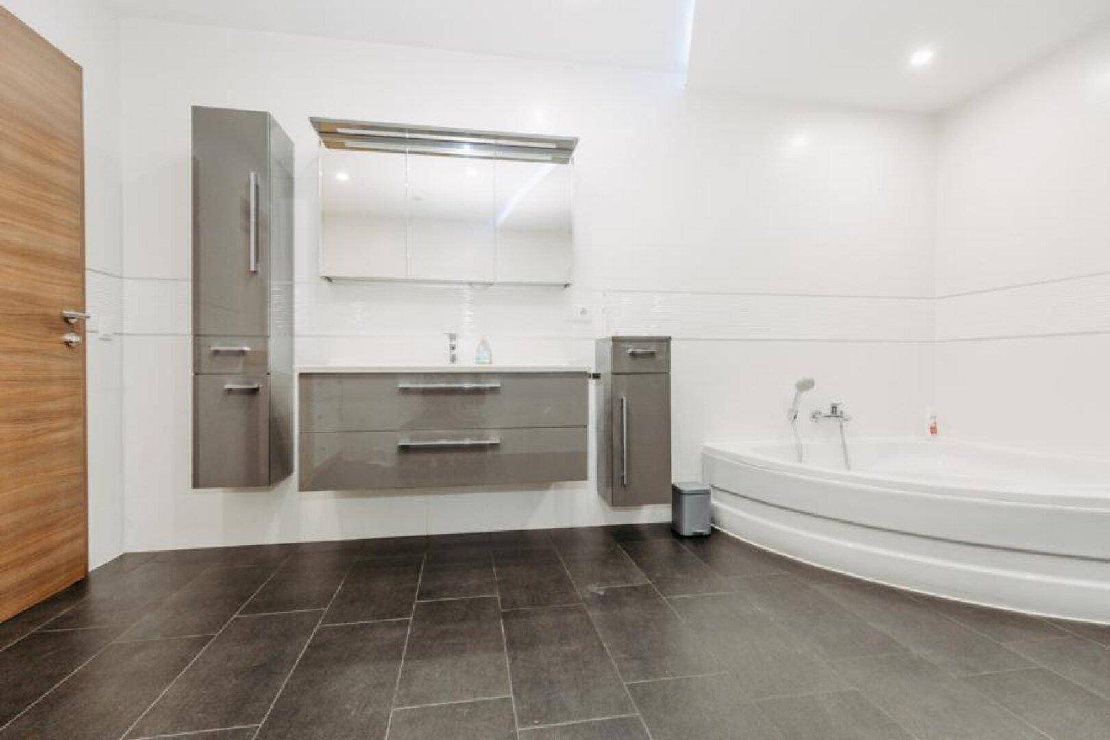 Modernes Badezimmer mit Eckbadewanne, großem Waschtisch und Spiegelschrank.