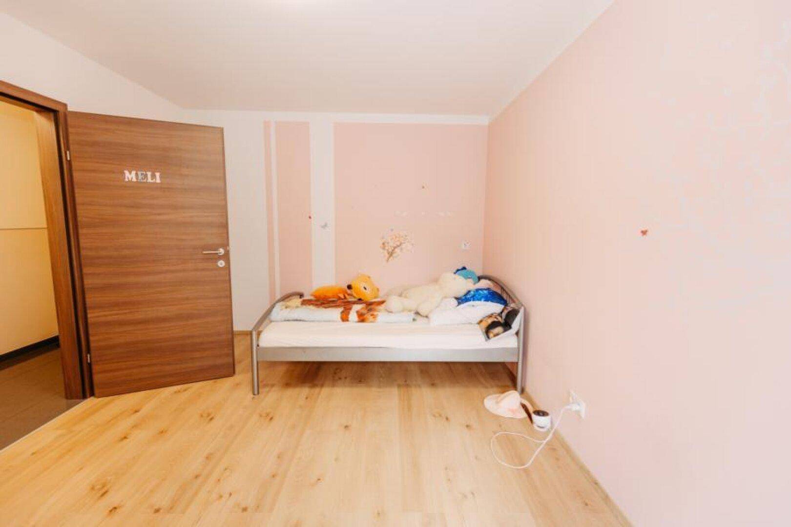 Gemütliches Kinderzimmer mit Einzelbett, hellem Holzboden und rosa Wänden.