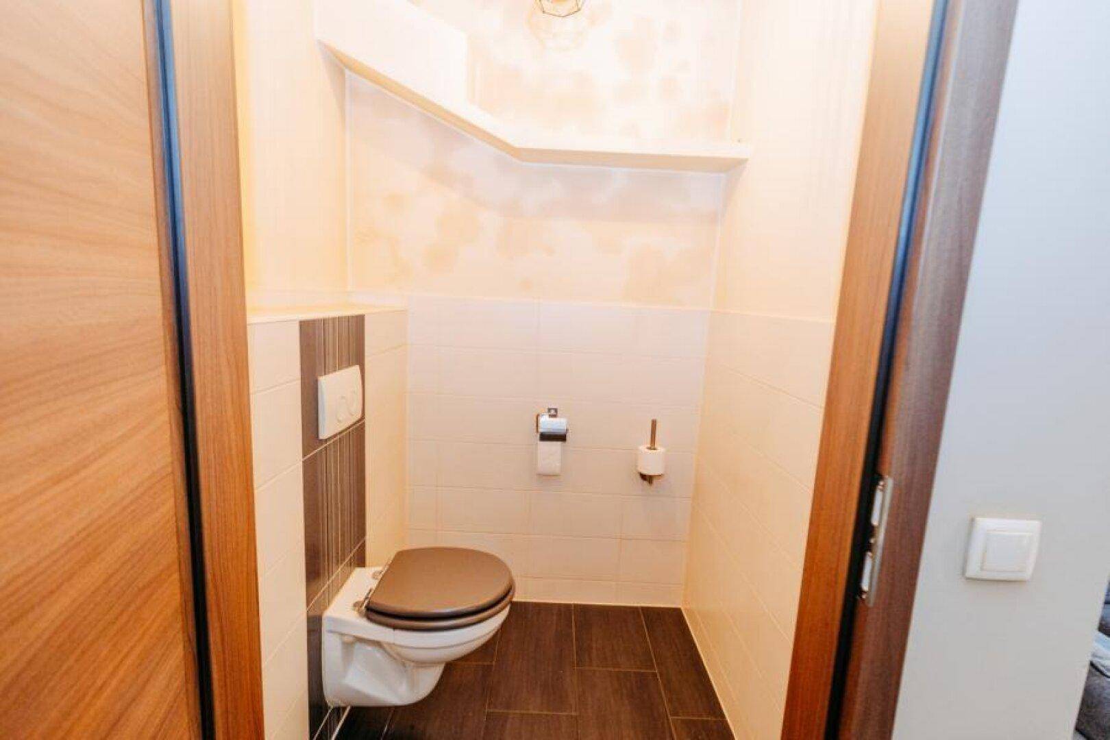 Kleines Gäste-WC mit Wand-WC, Fliesen und schlichtem Design.