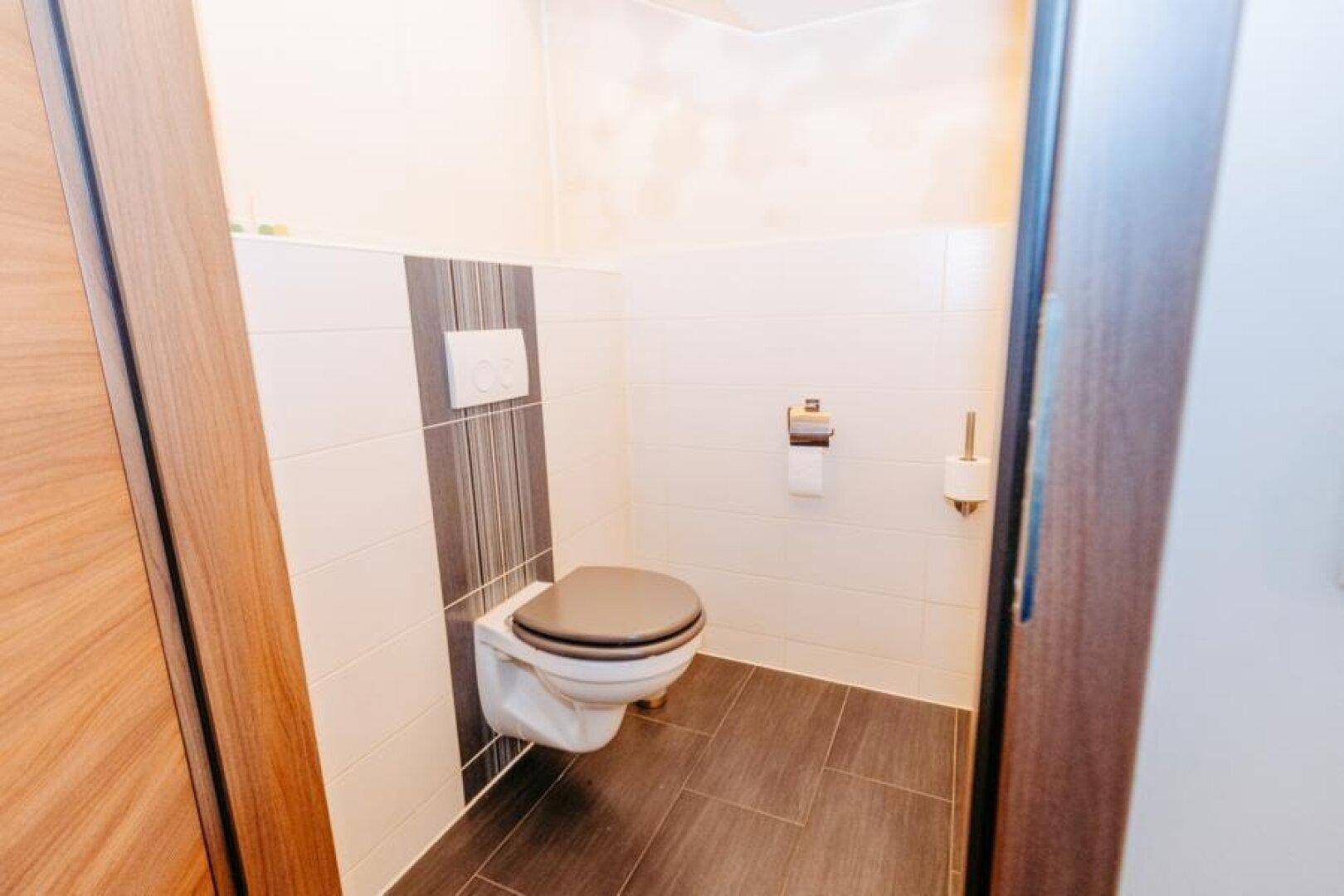 Funktionales Gäste-WC mit Wand-WC und Fliesen in neutralen Farben.