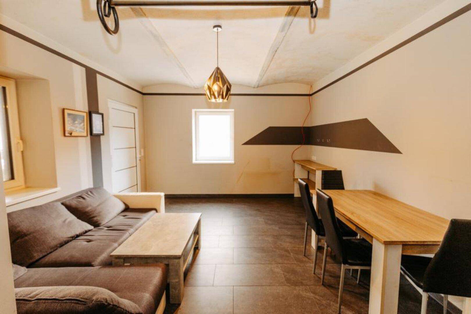 Gemütlicher Wohn-Essbereich mit Sofa, Holztisch und dekorativer Wandgestaltung.
