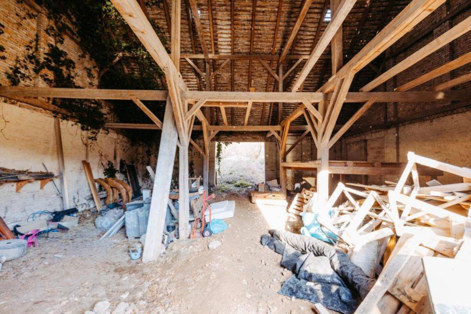 Rustikaler Scheuneninnenraum mit Holzbalkenkonstruktion und Blick ins Grüne.
