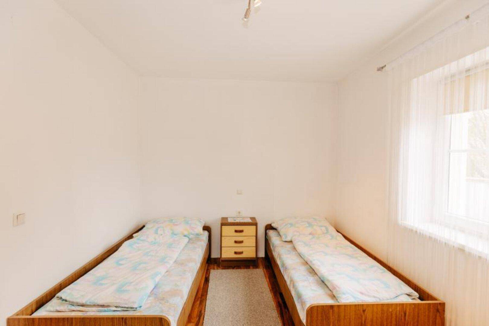 Helles Schlafzimmer mit zwei Einzelbetten, weiß gestrichenen Wänden und Fenster.