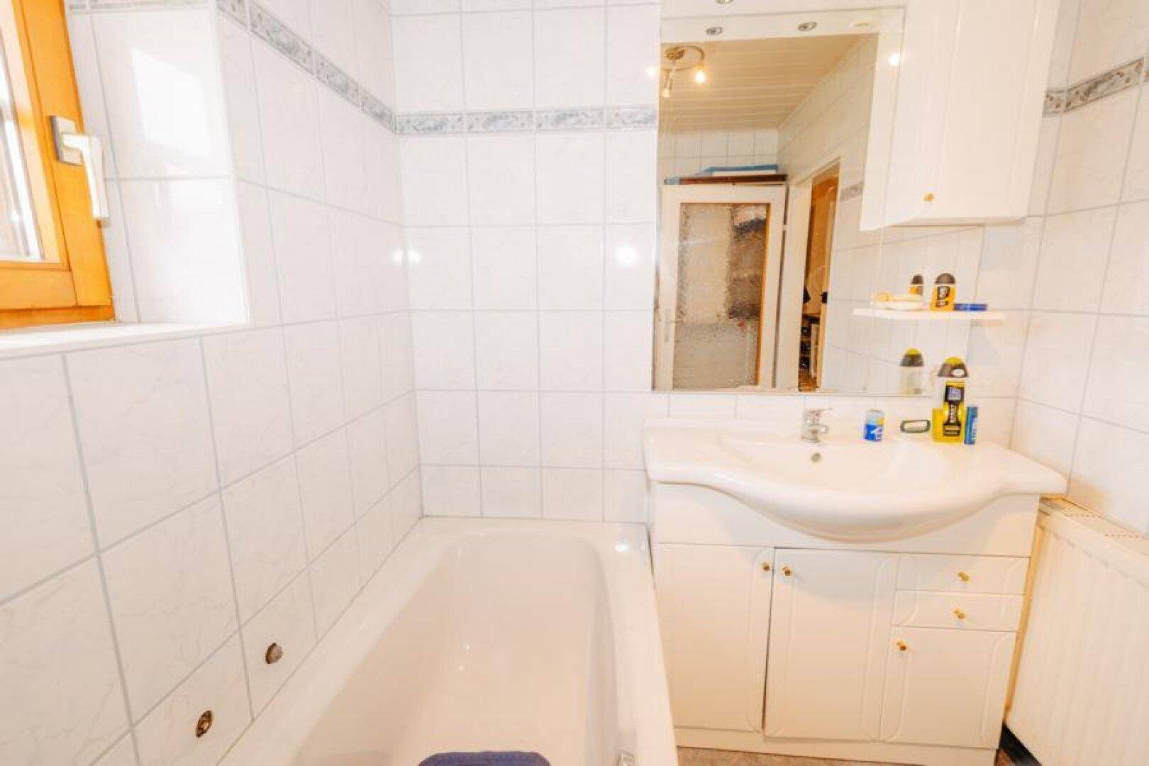 Badezimmer mit Badewanne, Waschbecken und Spiegelschrank über dem Waschtisch.