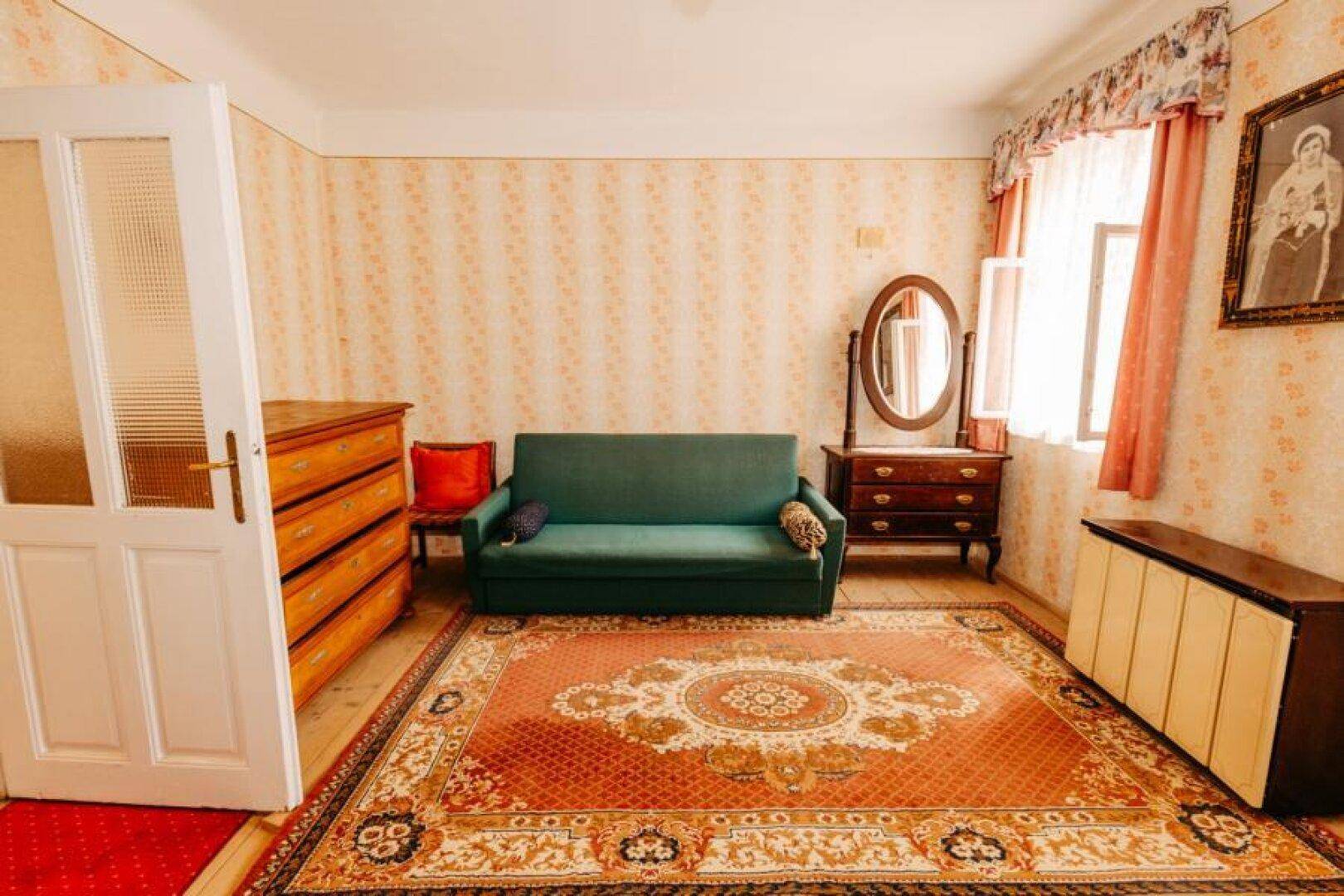 Wohnzimmer mit Sofa, Kommode und gemusterter Tapete in warmen Farbtönen.