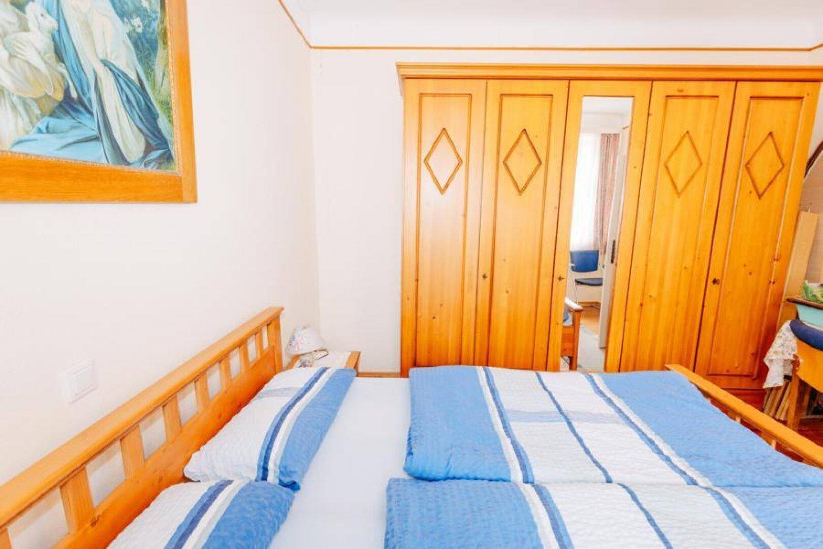 Schlafzimmer mit Doppelbett, Holzschrank und Spiegel für mehr Raumgefühl.