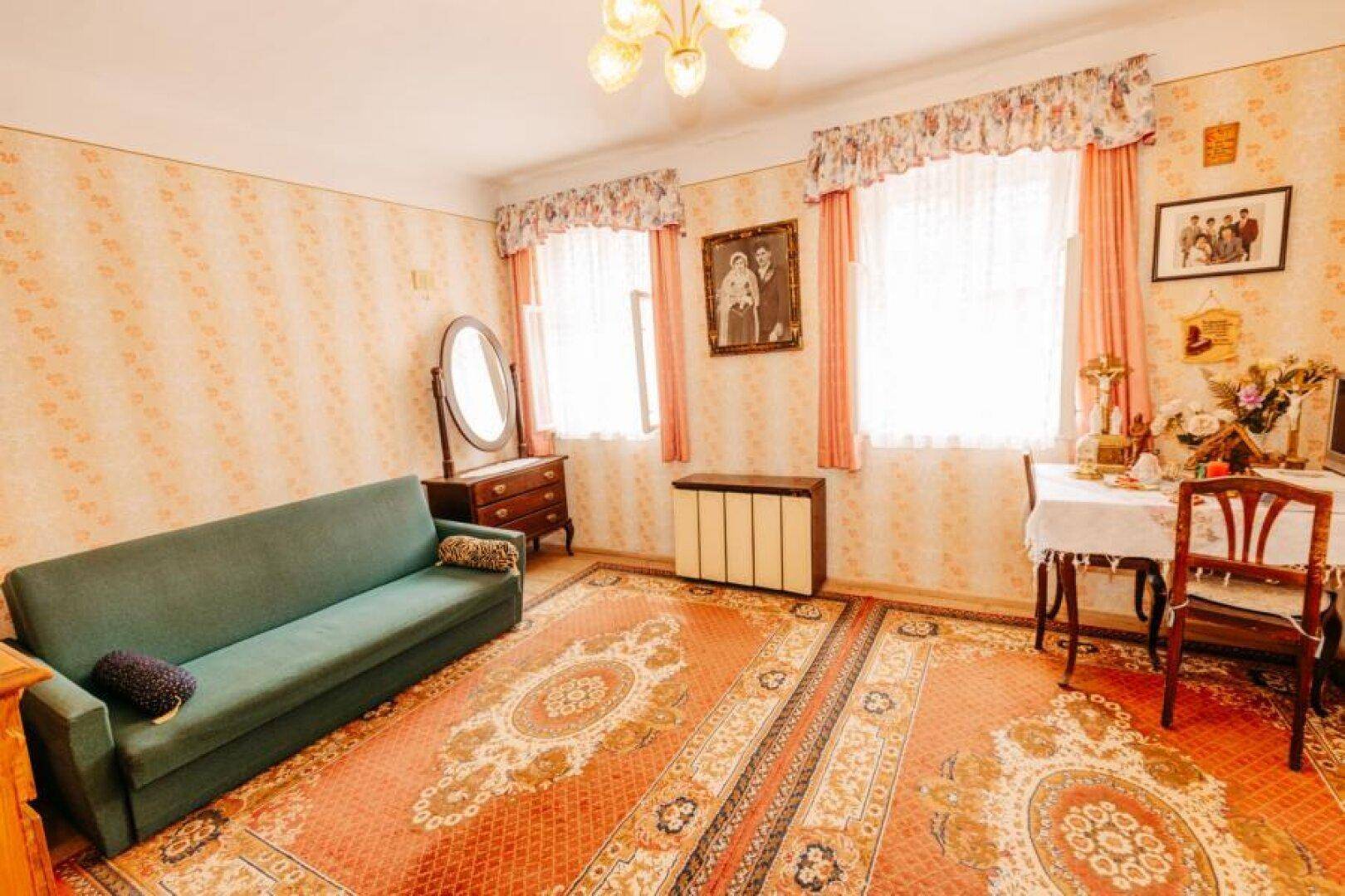 Wohnzimmer mit Sofa, Teppichboden und traditioneller Einrichtung in warmen Farben.