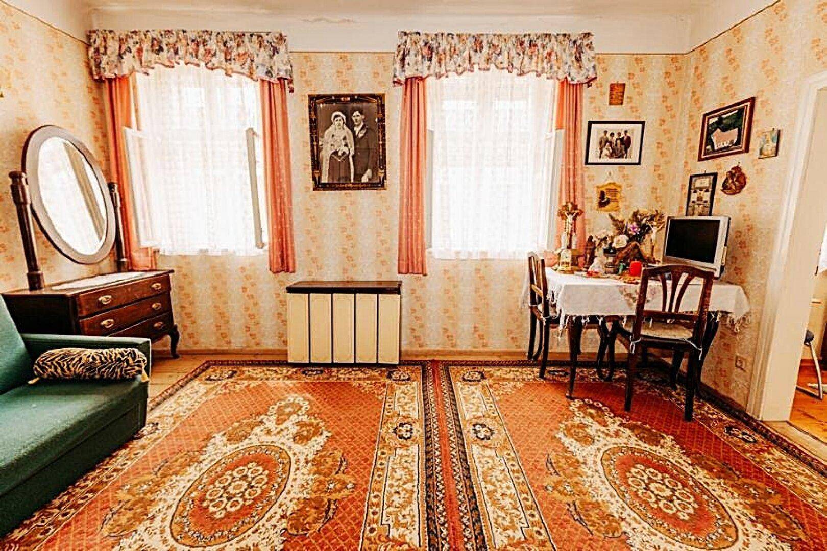 Gemütliches Wohnzimmer mit traditionellen Teppichen, floraler Tapete und Essbereich.