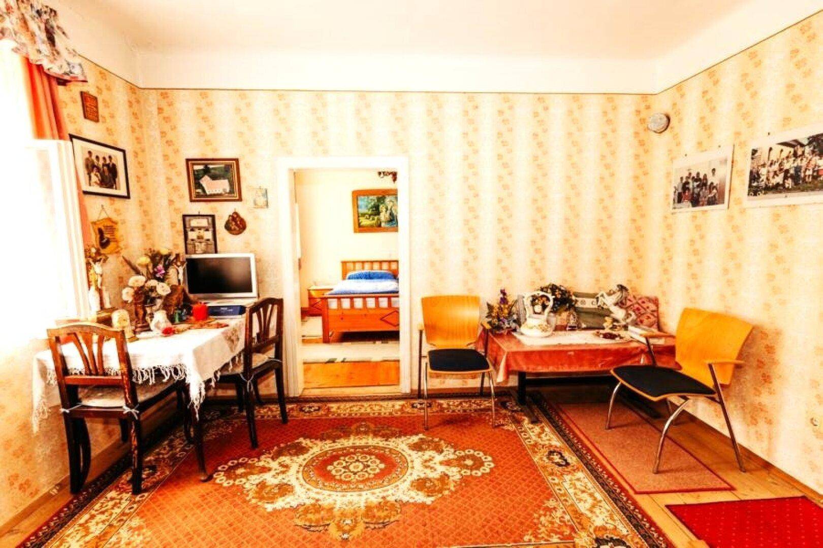 Helles Wohnzimmer mit gestreifter Tapete, traditionellen Teppichen und Zugang zum Schlafzimmer.