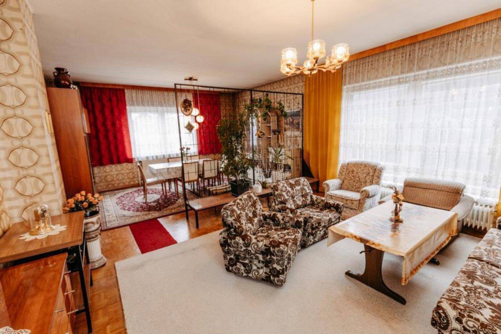 Geräumiger Wohn- und Essbereich im Vintage-Stil mit gemusterter Tapete und Teppichboden.
