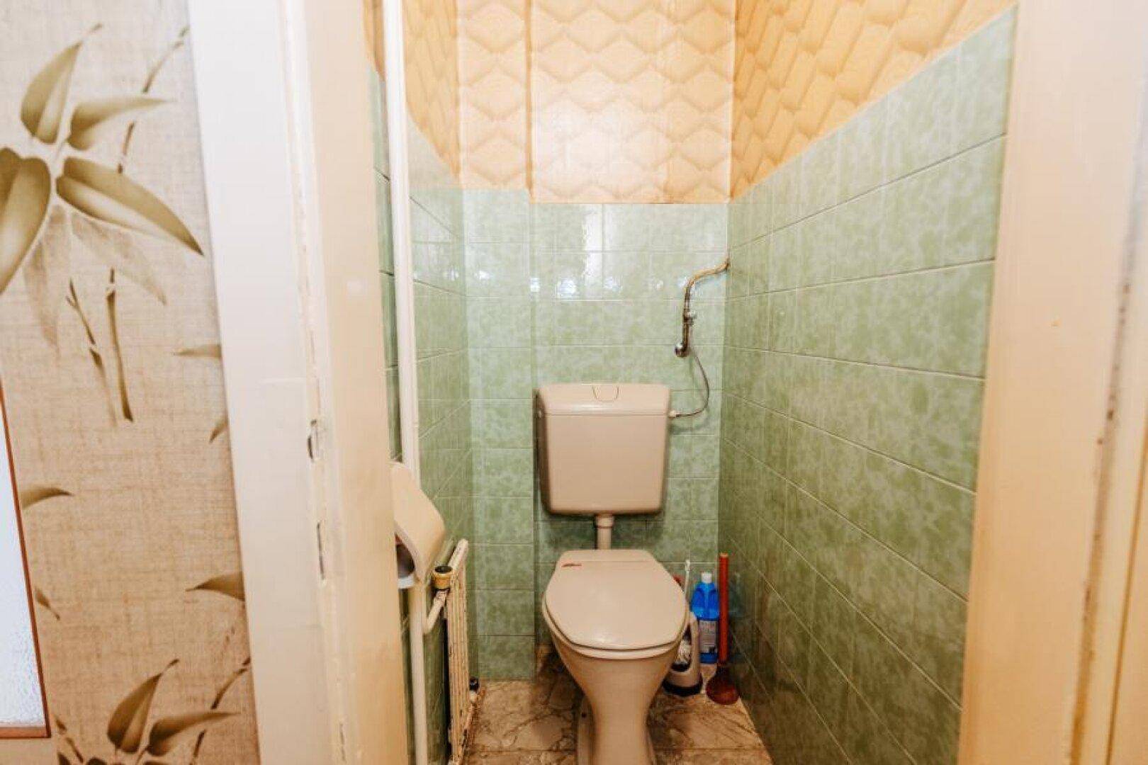 Kleines Gäste-WC mit grünen Fliesen und einfacher Toilette.