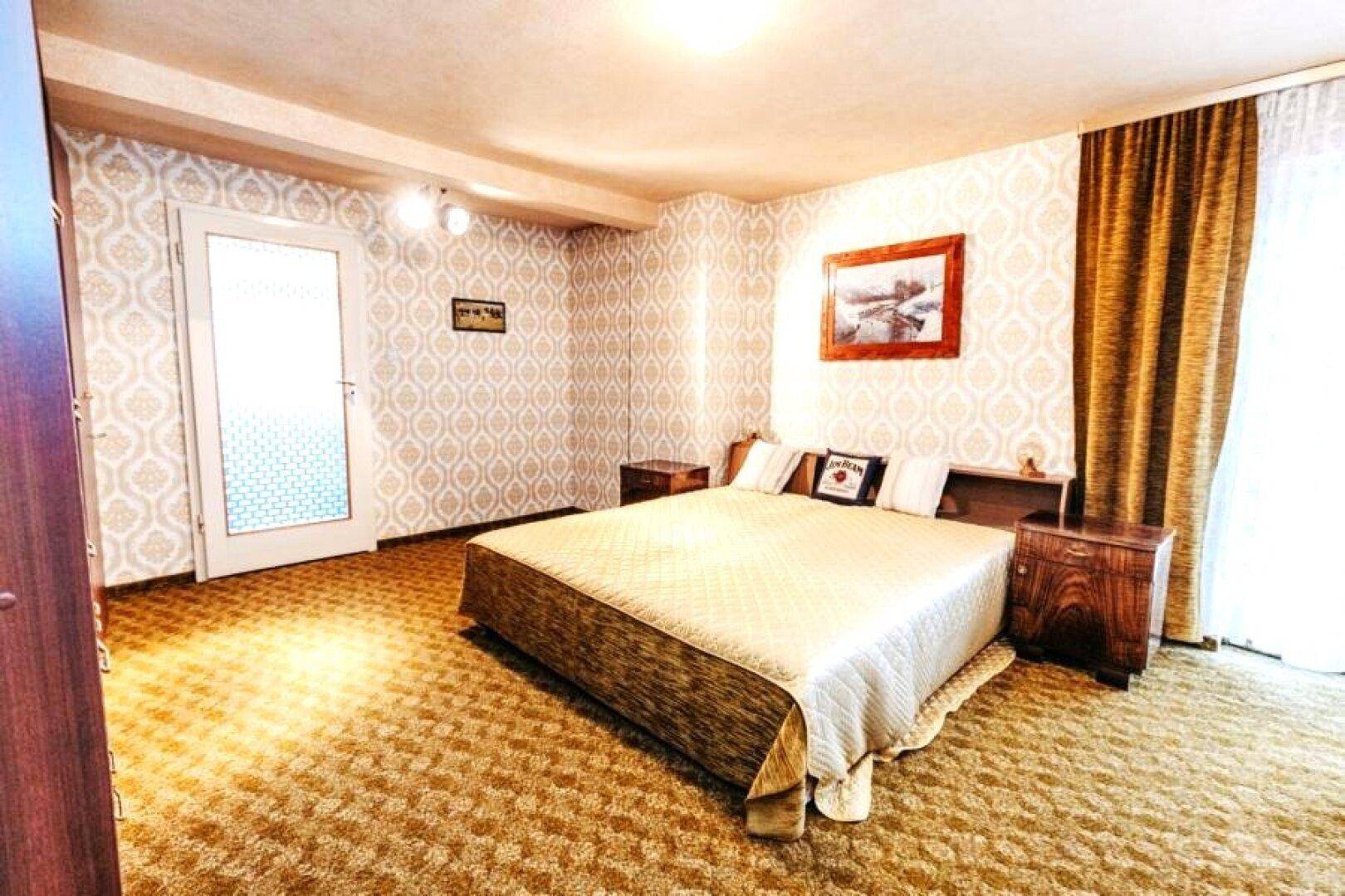 Schlafzimmer mit Doppelbett, gemusterter Tapete und Teppichboden.