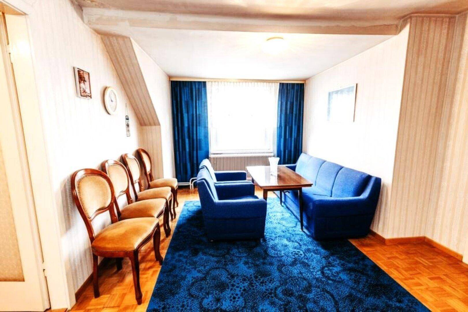 Wohnraum mit blauen Sofas, Teppichboden und Holzschränken.