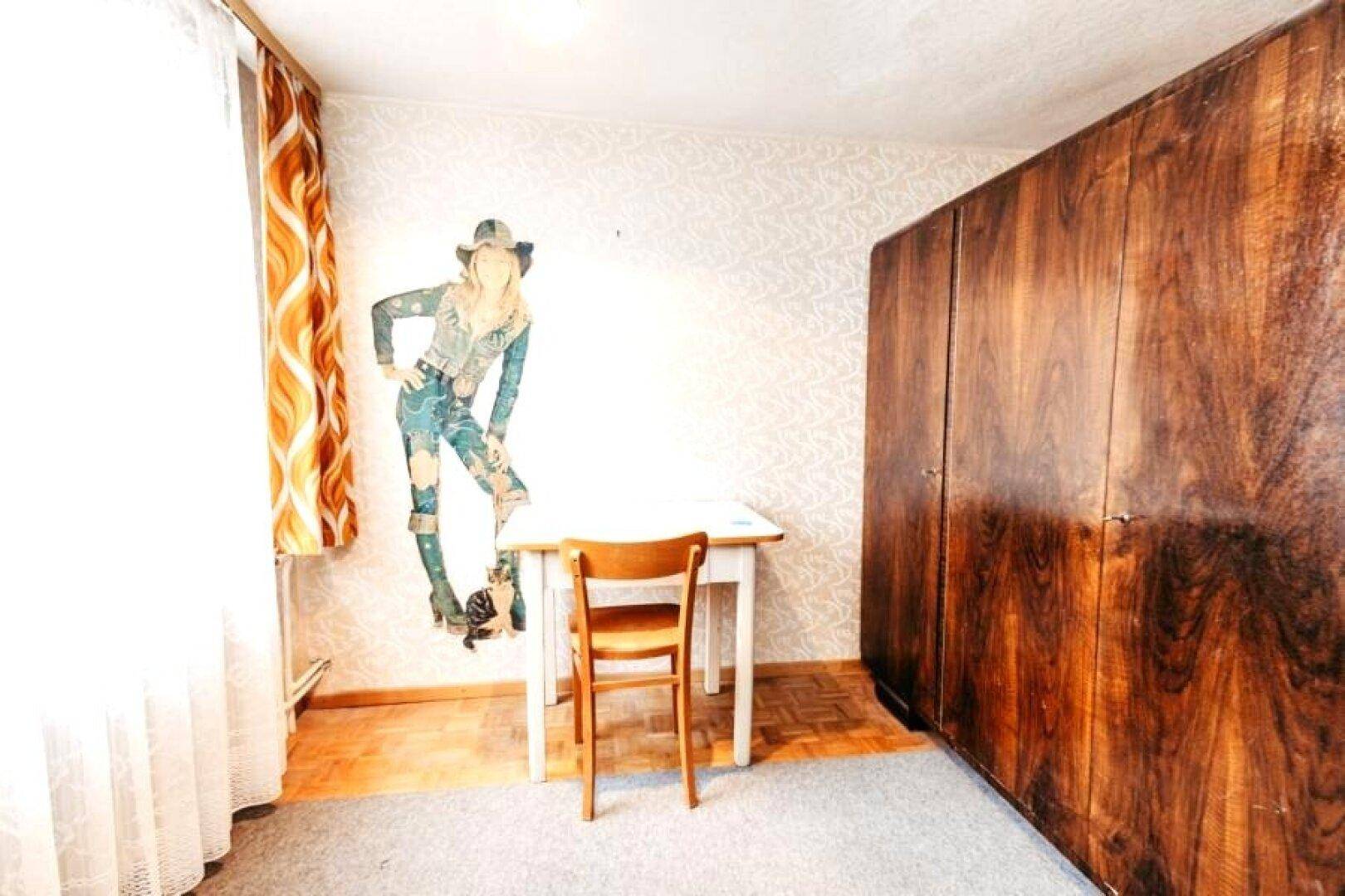 Kleines Zimmer mit Schreibtisch, großem Kleiderschrank und Teppichboden.