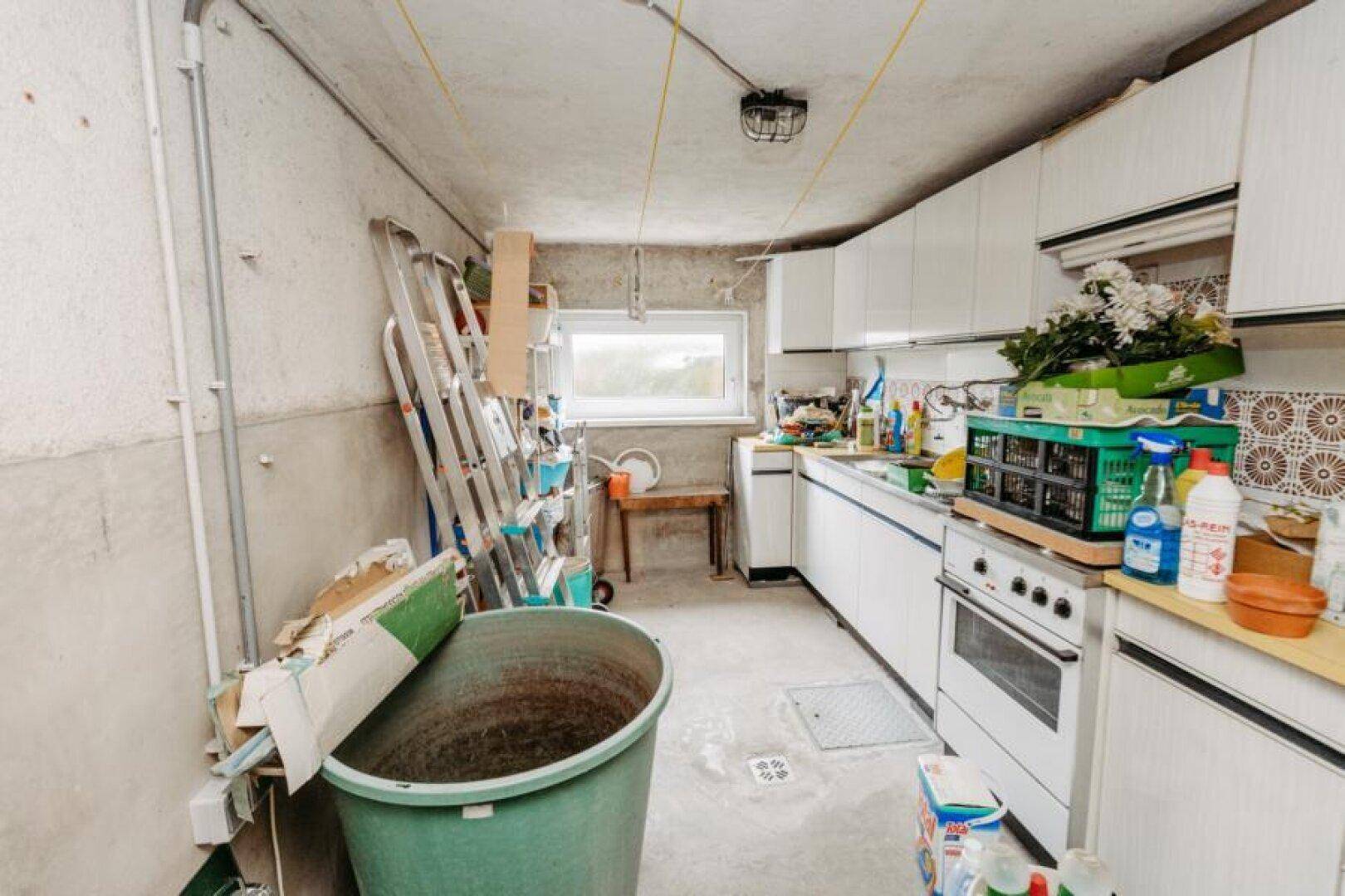 Hauswirtschaftsraum im Keller mit Spüle, Schränken und Lagerflächen.