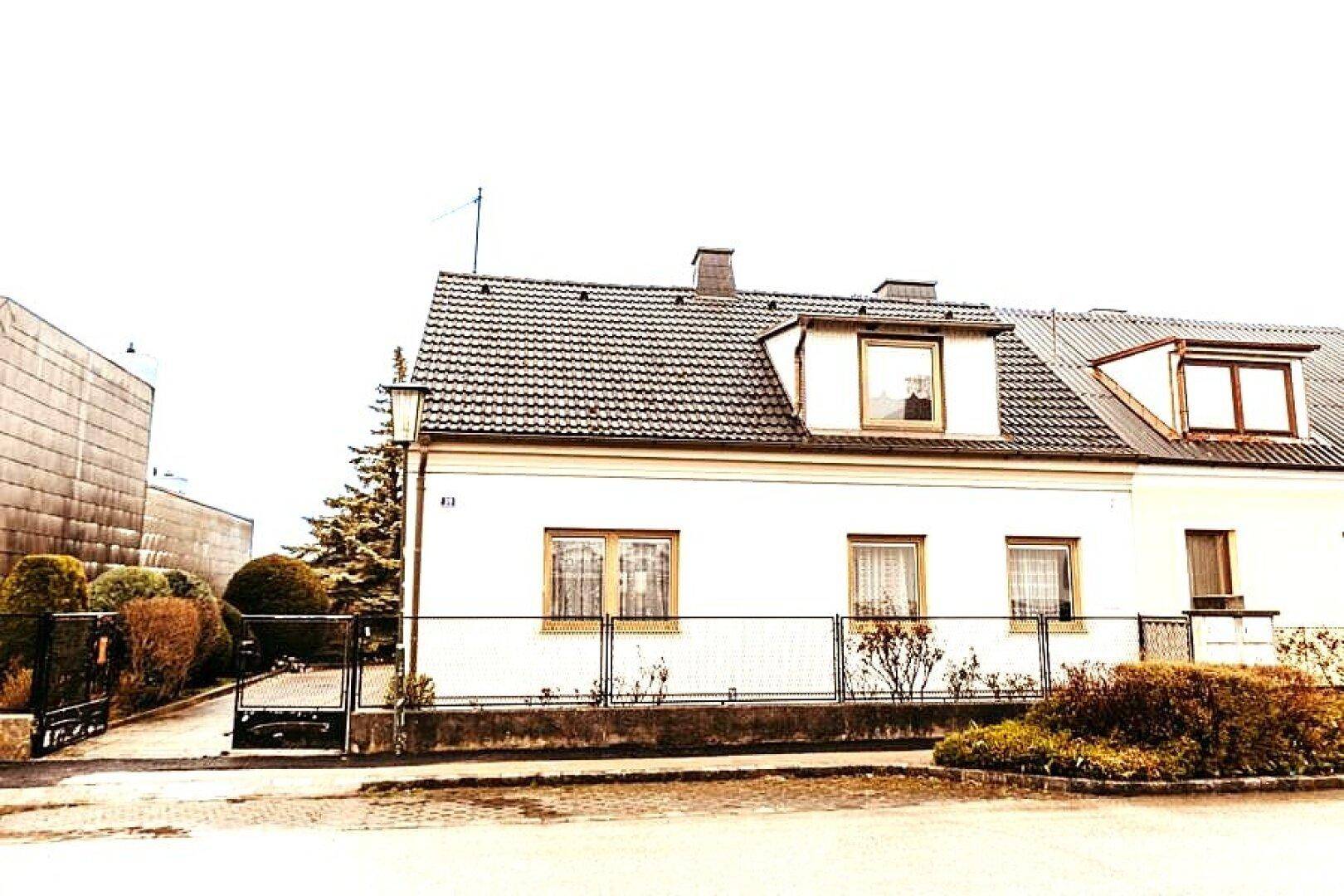 Ansicht des weißen Einfamilienhauses mit Dachgauben und gepflegtem Vorgarten.