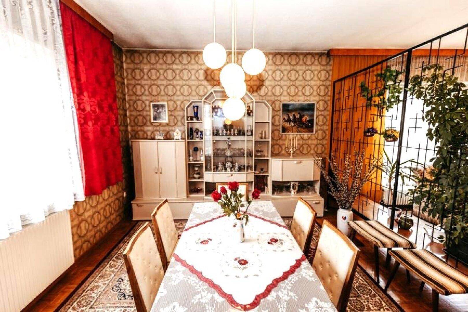 Essbereich im Vintage-Stil mit großem Esstisch, Vitrinenschränken und gemusterter Tapete.