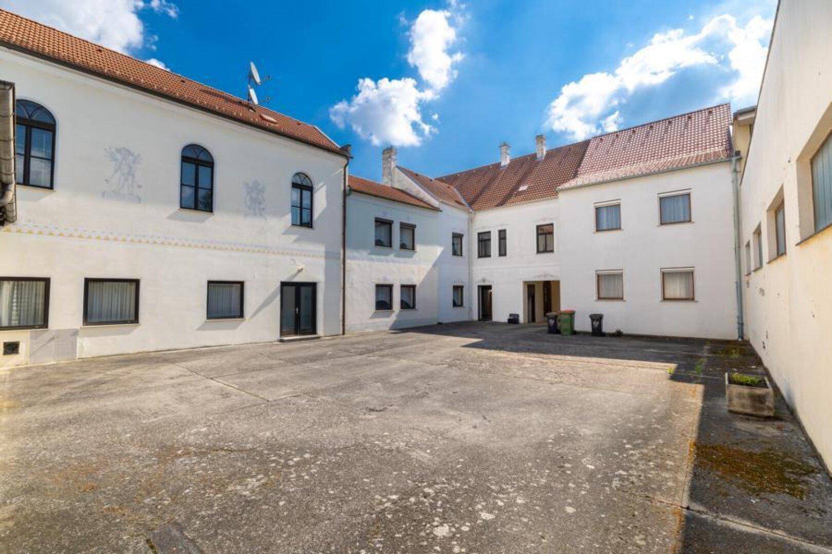 Großer gepflasterter Innenhof umgeben von Gebäuden unter blauem Himmel.