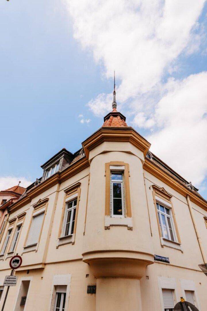 Detailansicht des markanten Eckturms und der oberen Fassade des historischen Gebäudes.