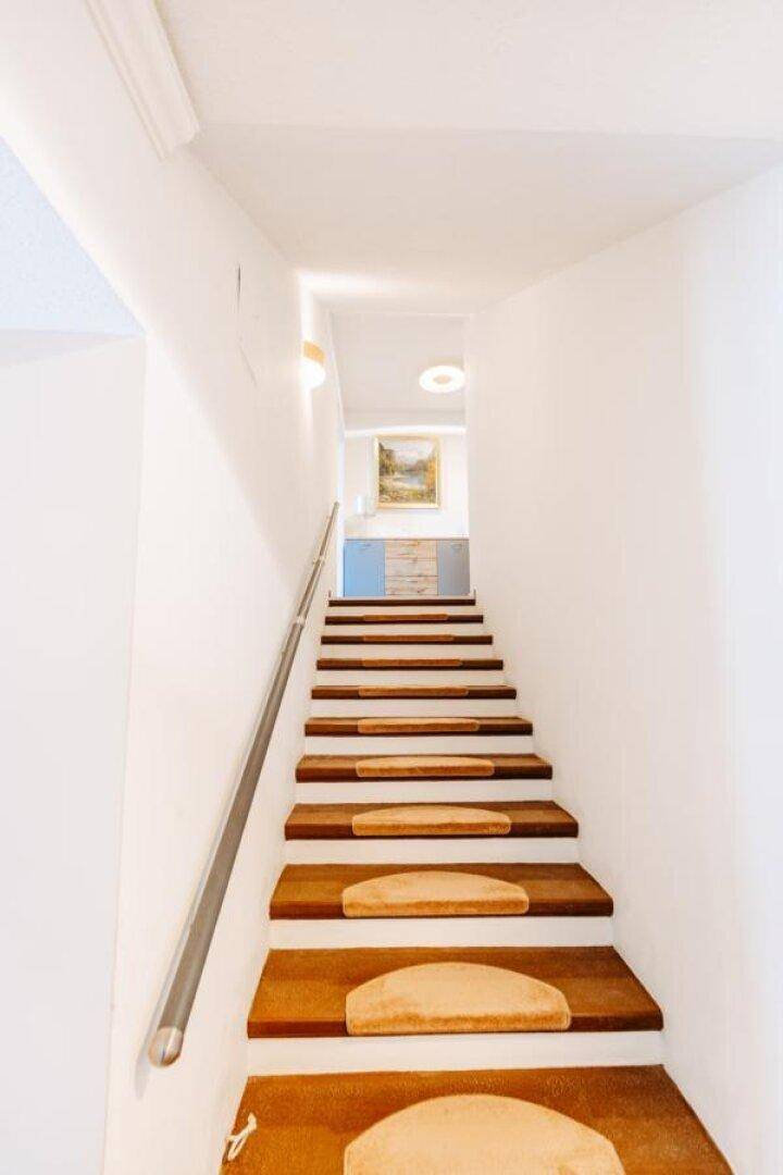 Holztreppe mit Metallgeländer führt in die oberen Etagen des Hauses.