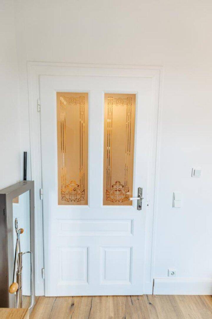 Weiße Innentür mit dekorativen Glaspaneelen und eleganten Mustern.