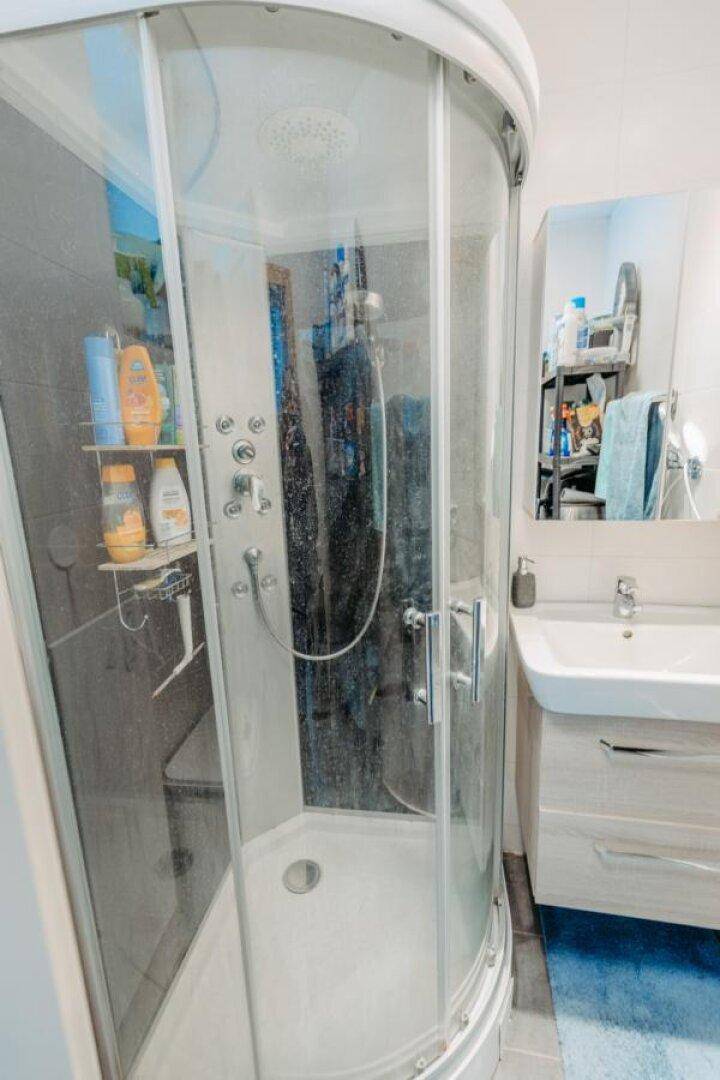 Badezimmer mit moderner Duschkabine und Einzelwaschbecken mit Unterschrank.