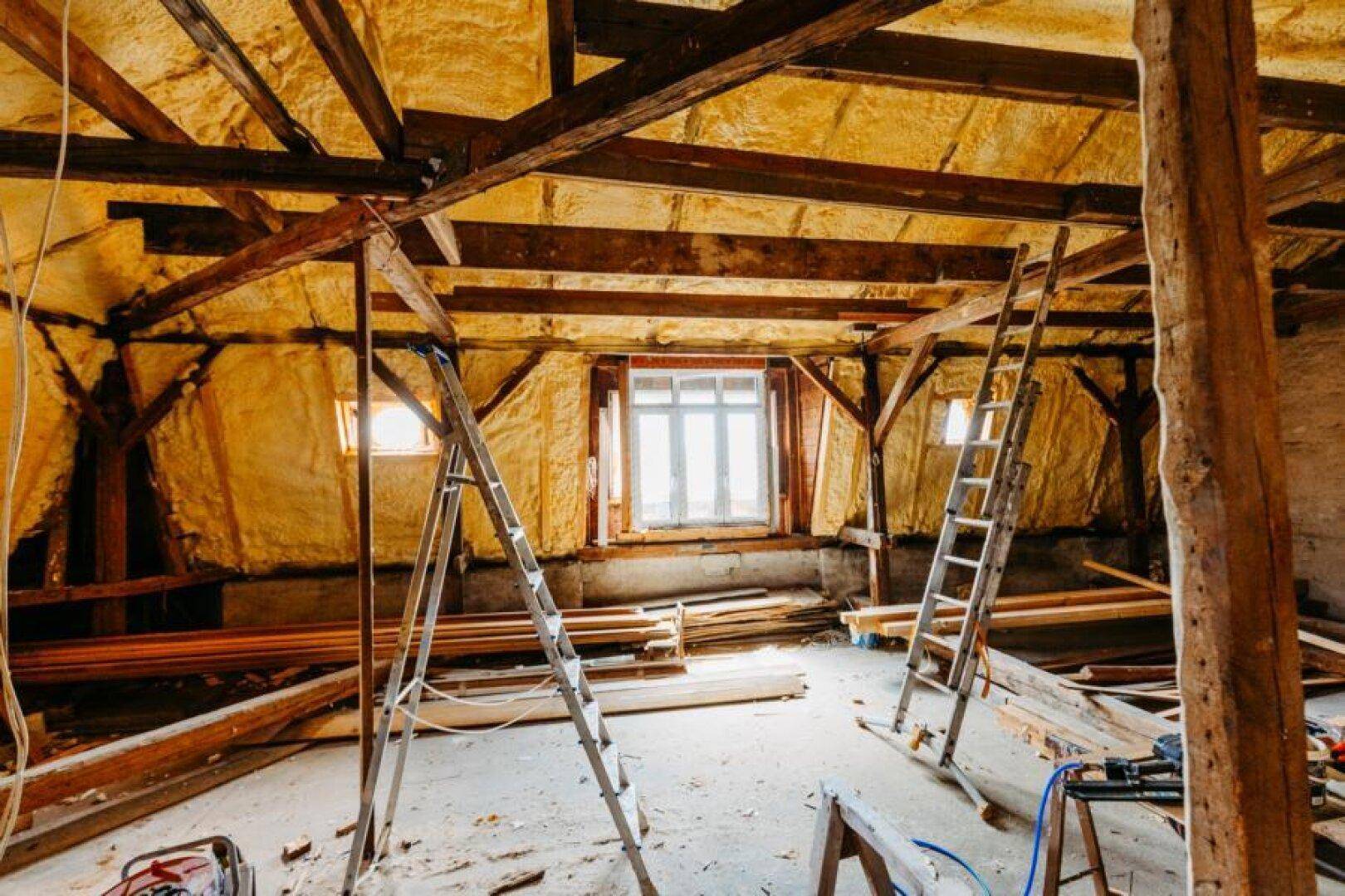 Großer Dachbodenbereich mit Holzbalken und Isolierung, bereit für den Ausbau.