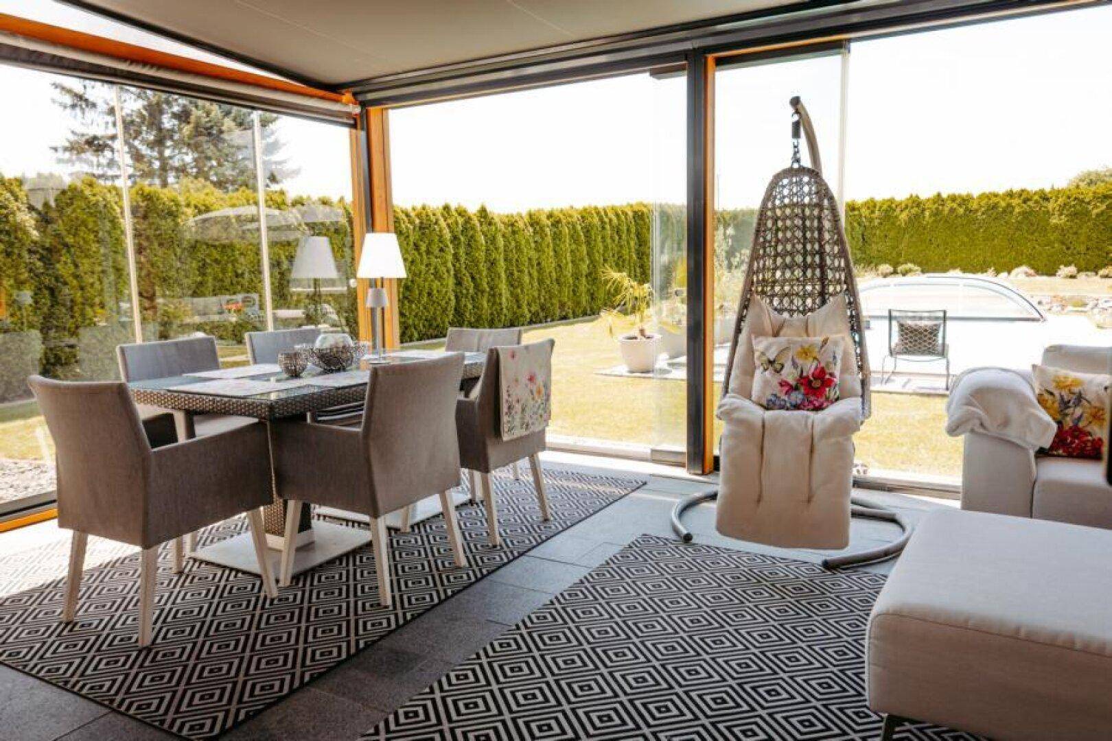 Essbereich im Wintergarten mit modernem Tisch, Stühlen und einem gemütlichen Hängesessel.