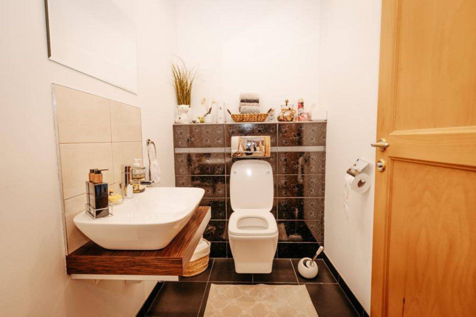 Modernes Gäste-WC mit stilvollem Waschbecken, Wand-WC und dunklen Fliesen.