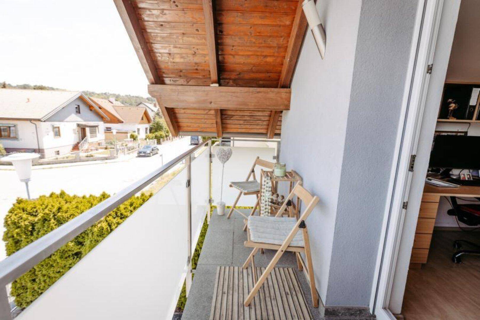 Kleiner Balkon mit Holzdach, Blick auf die Straße und umliegende Häuser.