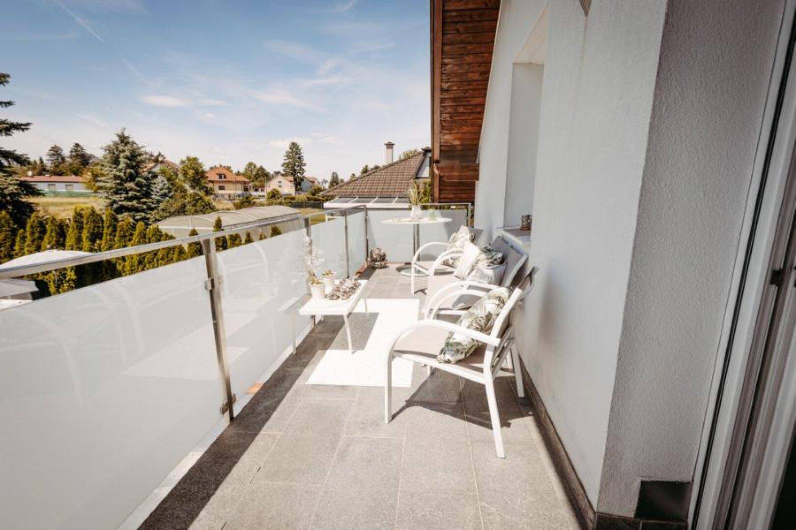 Geräumiger Balkon mit modernen Gartenmöbeln und Blick auf die Umgebung.