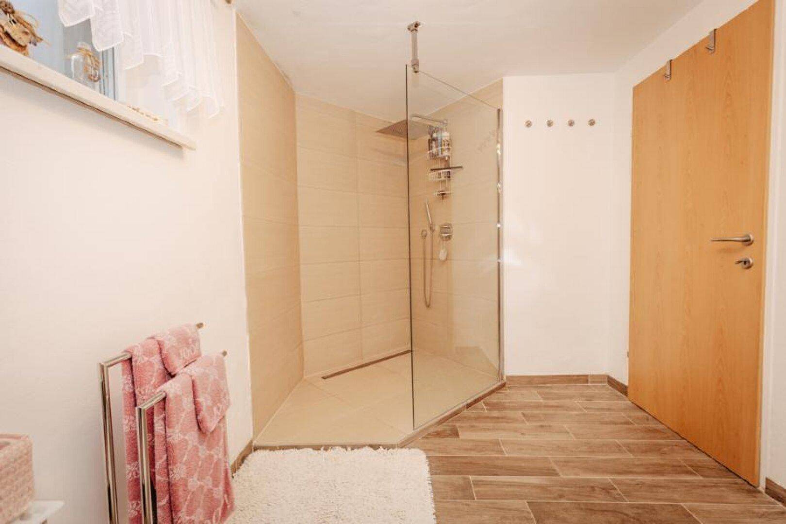 Modernes Badezimmer mit begehbarer Dusche, Holzoptikfliesen und Fenster.