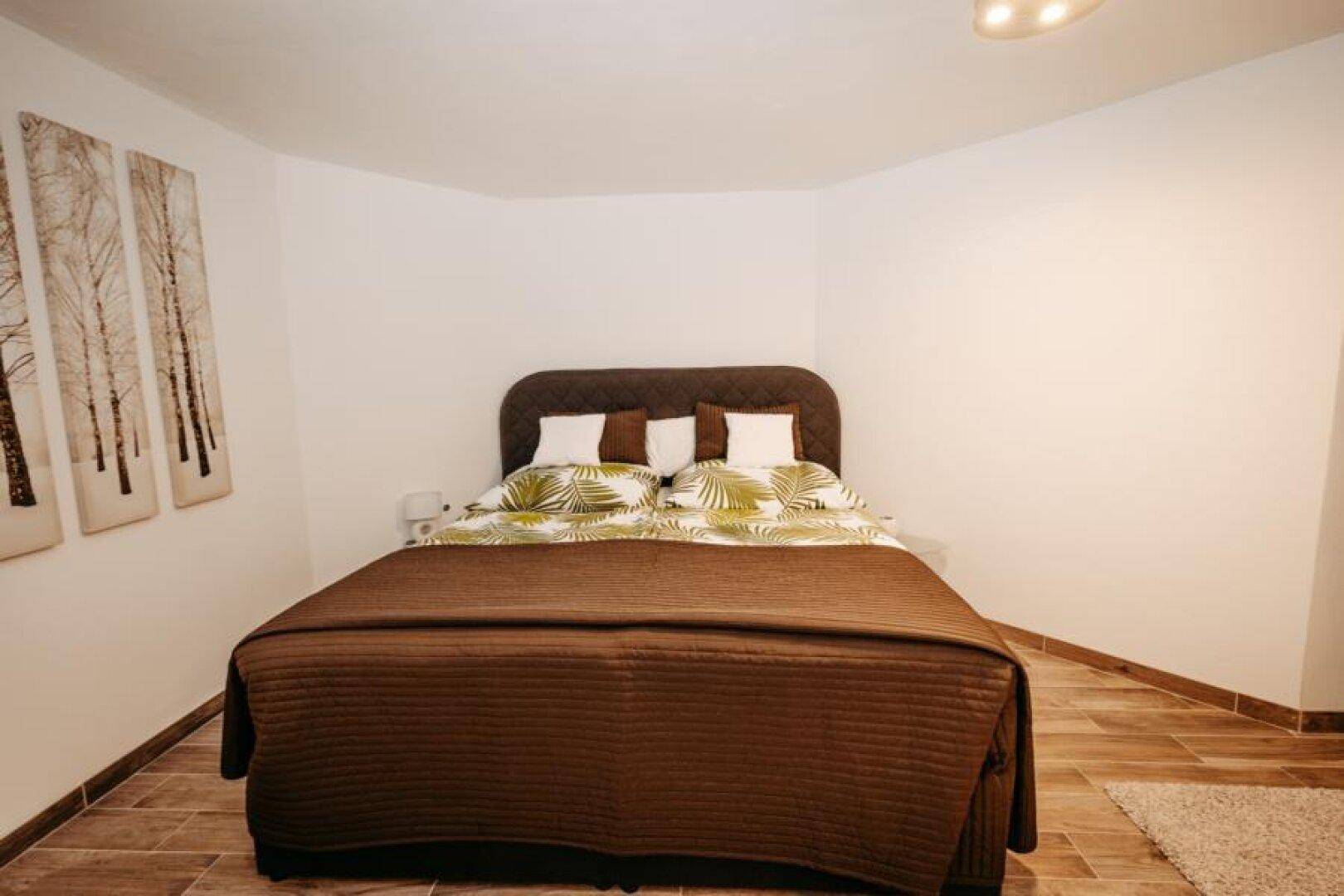 Schlafzimmer mit Doppelbett, Holzboden und schlichter, moderner Einrichtung.