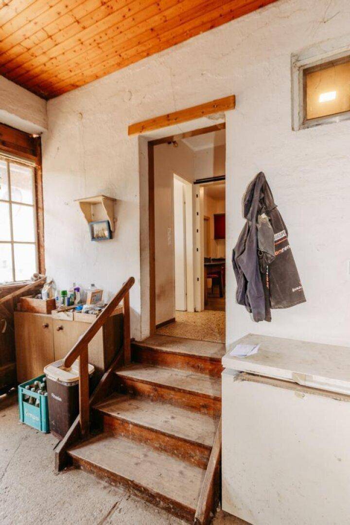 Eingangsbereich mit Holztreppe, die zu weiteren Räumen führt, und einer Holzdecke.