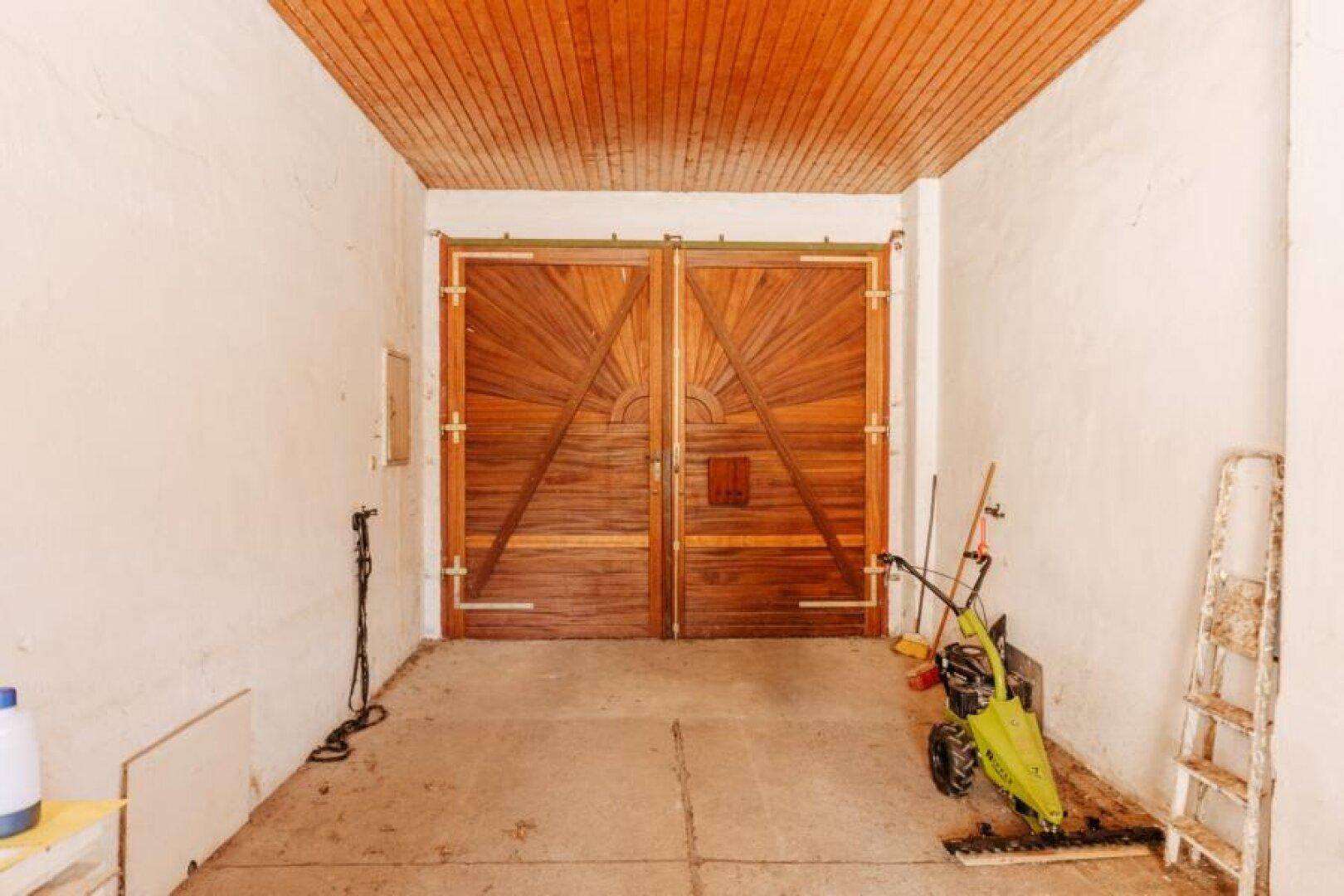 Innenansicht einer Garage mit großen, rustikalen Holztüren und einer Holzdecke.