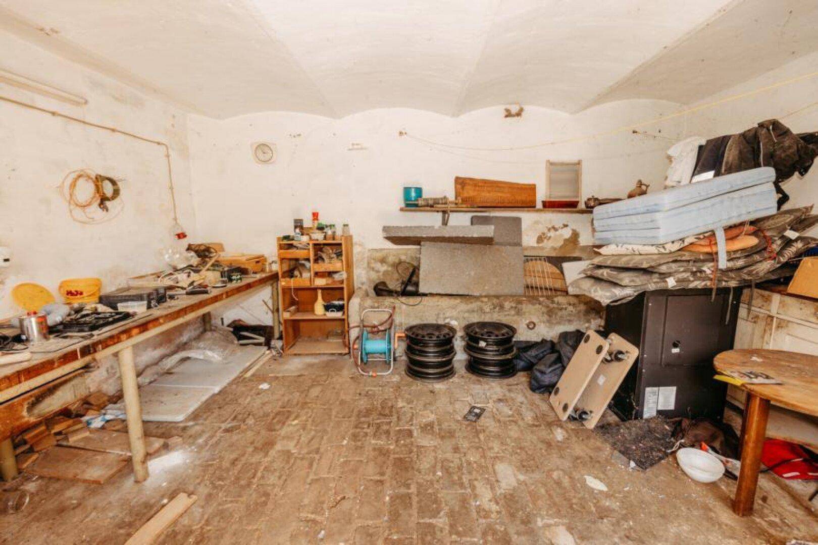 Geräumiger Werkstattraum mit gewölbter Decke, Werkbänken und verschiedenen Materialien.