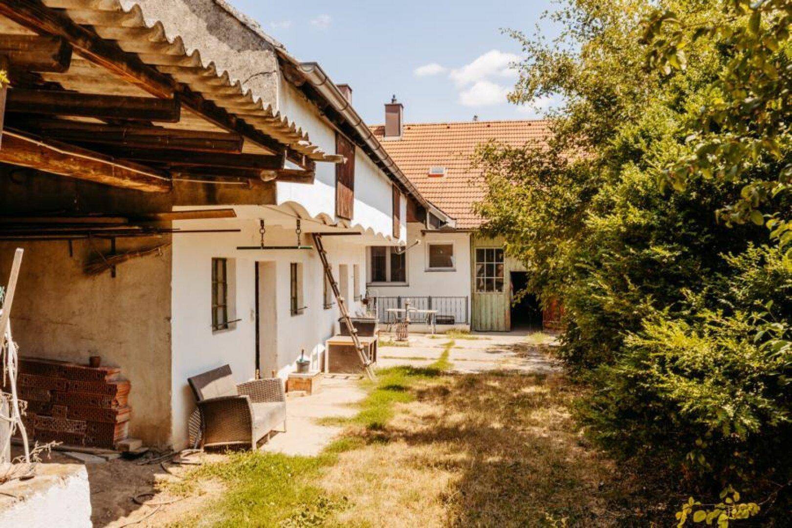 Weiter Blick über den Innenhof mit verschiedenen Gebäudeteilen und viel Grün.