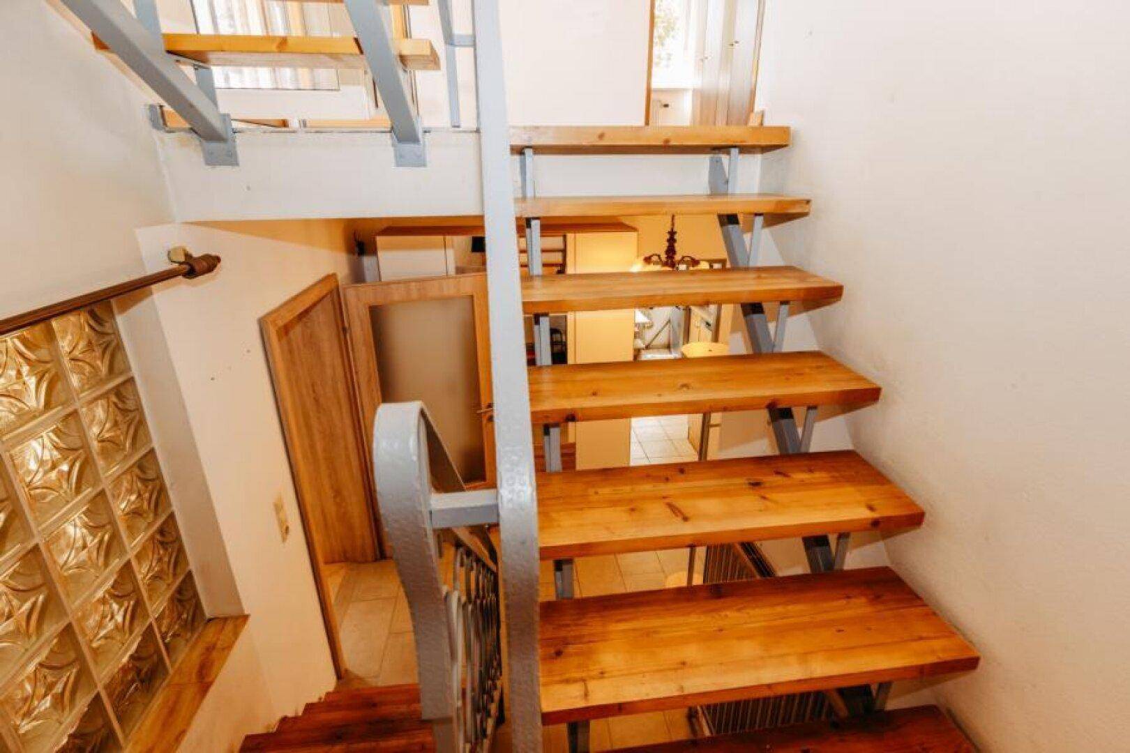 Holztreppe mit Metallgeländer, die verschiedene Ebenen des Hauses verbindet.