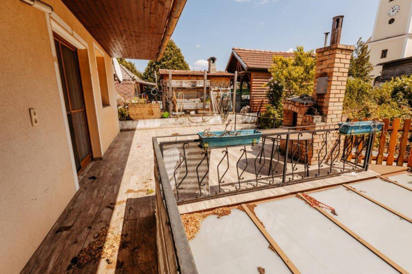 Große Terrasse mit Außenkamin und Blick auf die Umgebung und einen Kirchturm.