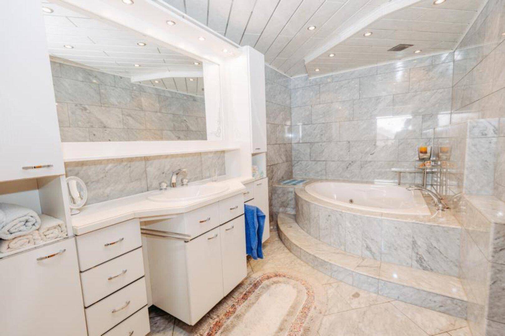 Geräumiges Badezimmer mit Eckbadewanne, großem Waschtisch und hellen Marmorfliesen.